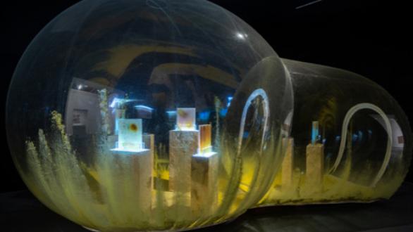 Anicka Yi, Le Pain Symbiotique, 2014 PVC dome, projector, single-channel video, glycerin soap, resin, dough, pigmented powder, plastic, Mylar, beads, tempera paint, cellophane, 213.36 × 396.24 cm Installation view, Museum of Contemporary Art, Los Angeles, 2019 Courtesy the artist, Gladstone Gallery, New York and Brussels, and 47 Canal, New York