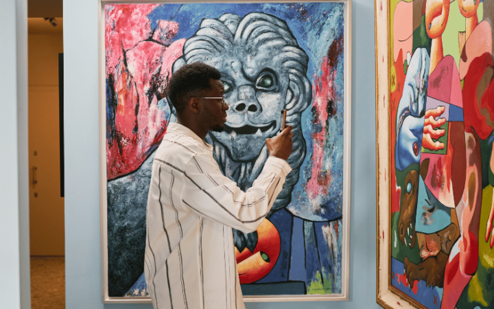 Un visitante utiliza su teléfono móvil ante varias pinturas, una imagen que refleja cómo la fotografía está transformando nuestra forma de mirar, disfrutar y recordar el arte en los museos.