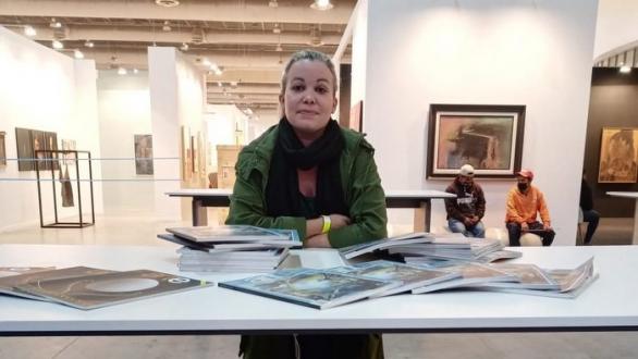 Nelia Moreno en mesa p18 de Zona Maco mostrando revistas Arte por Excelencias 