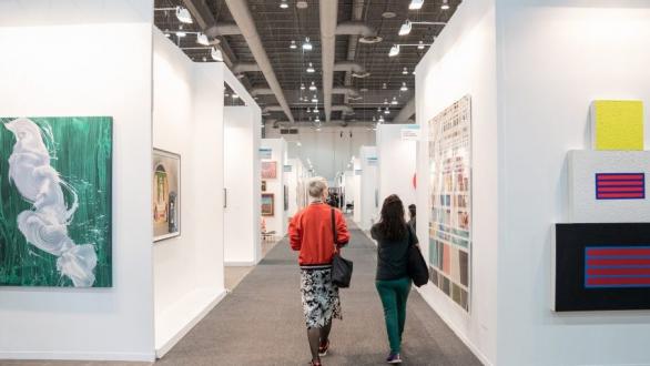 personas caminan por una muestra de artes visuales en la feria zona maco 
