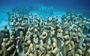 Esculturas del Museo Subacuático de Arte de Cancún cubiertas por organismos marinos y rodeadas de peces