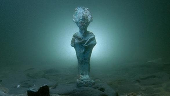 Bronze statuette of Osiris and lead votive barque on the seabed in Thonis-Heracleion, Bay of Aboukir, Egypt (SCA 1081, 1039).  Image: Christoph Gerigk © Franck Goddio, Hilti Foundation.