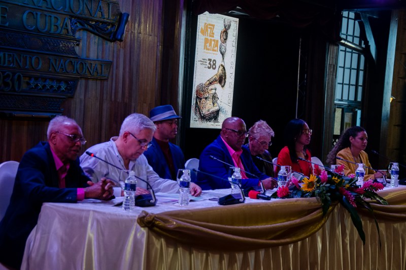 De izquierda a derecha en las imágenes del panel en la conferencia de prensa: Rodoulfo Vaillant, director del Jazz Plaza en Santiago de Cuba; Roberto Fonseca, compositor y director artístico del Festival; Víctor Rodríguez, presidente del evento; Bobby Carcassés, fundador del Jazz Plaza; Indira Fajardo, presidenta del Instituto Cubano de la Música; y Lied Lorain, periodista.